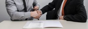 Imagen de dos personas estrechando la mano tras firmar un contrato